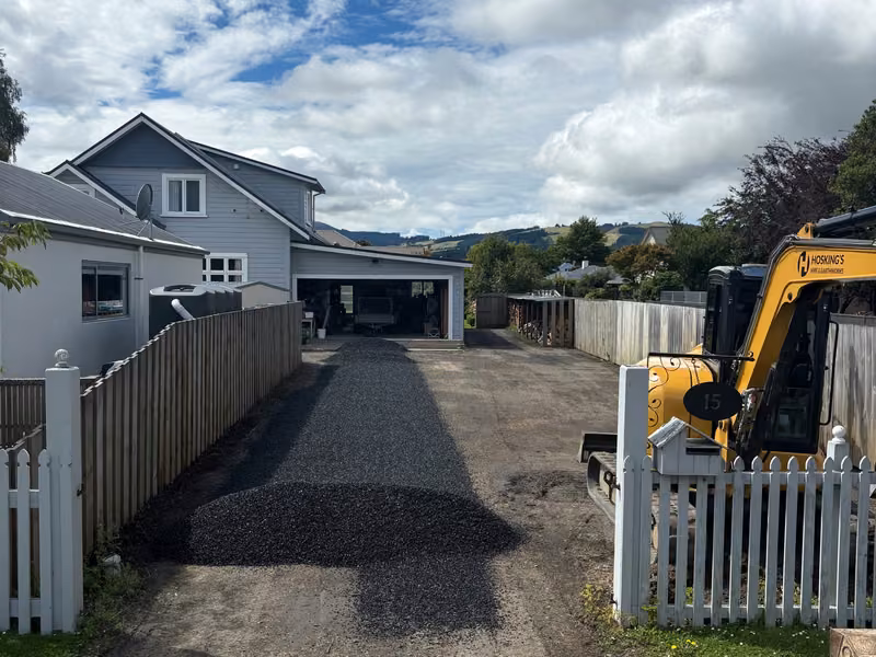 Compact excavator working on a residential driveway and access area