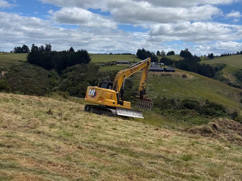 Excavator working across sloping rural ground