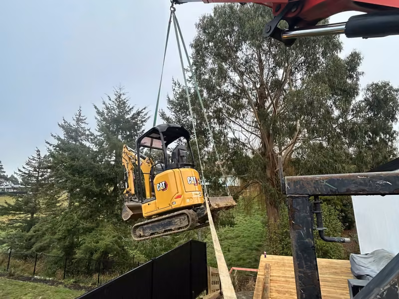 Mini excavator being lifted into a restricted-access work area
