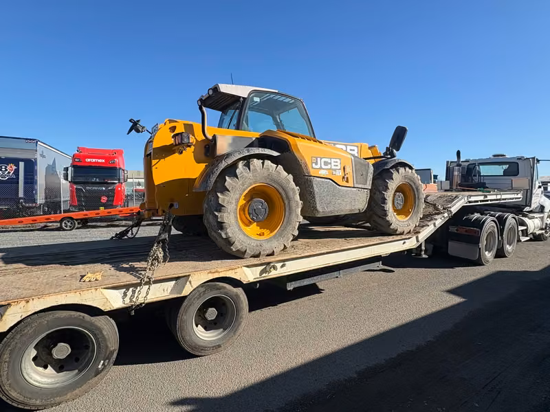 Telehandler secured on a transporter for machinery relocation
