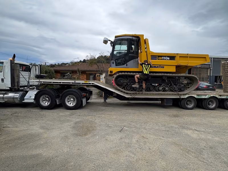 Tracked dumper loaded on a low-loader for transport