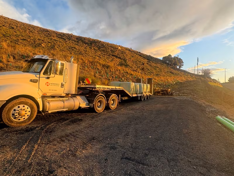 Hosking's truck and flat-deck trailer parked on a gravel work site